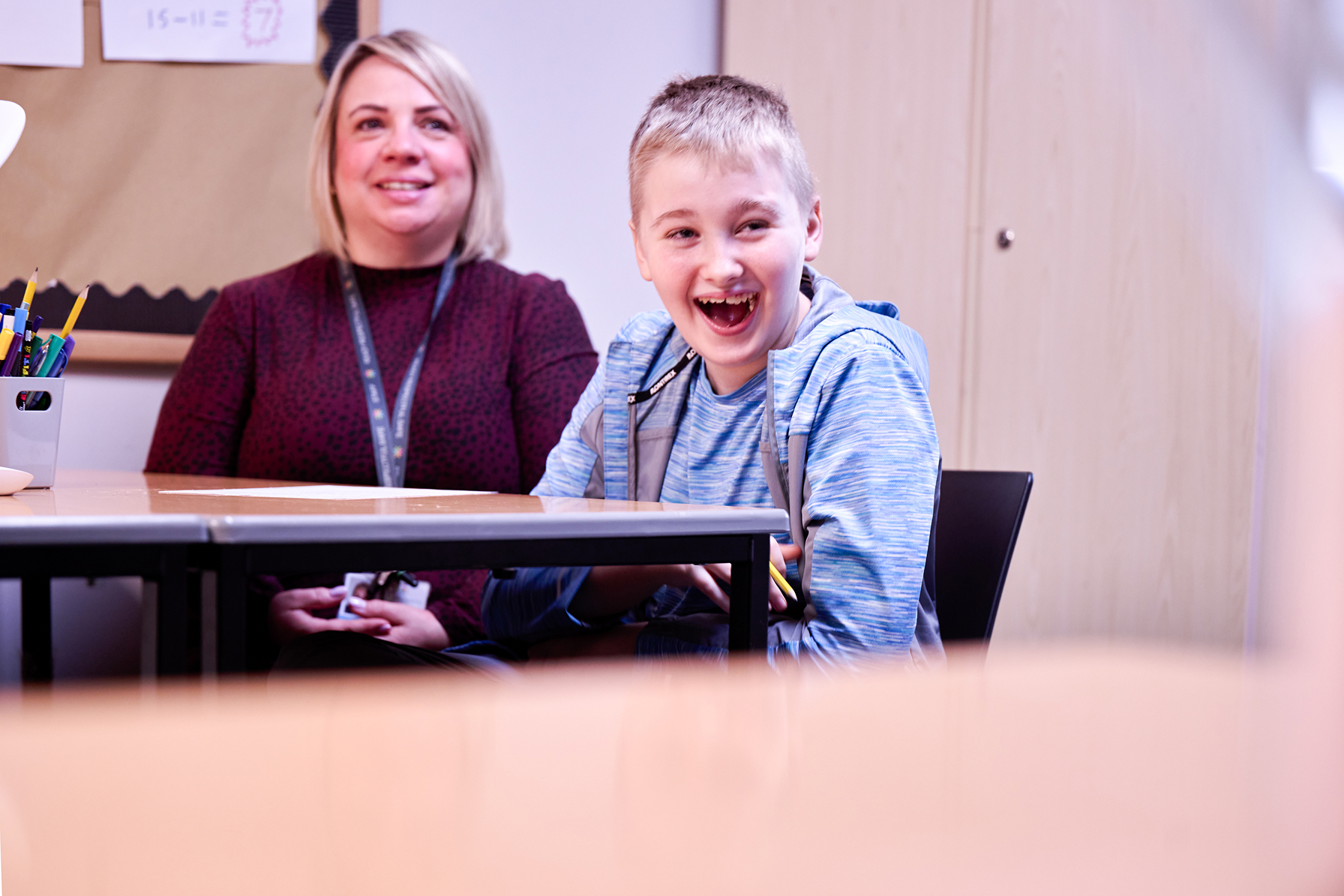 A school child and teacher laughing with a wide smiles
