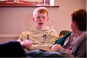 Two schoolboys sit together on a sofa, chatting
