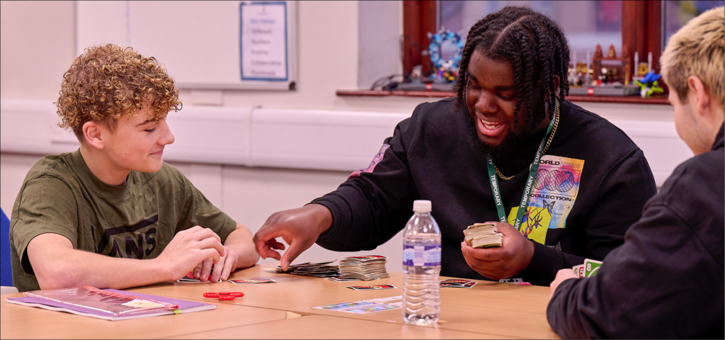 A teacher playing "UNO" with 2 students. Everyone smilling